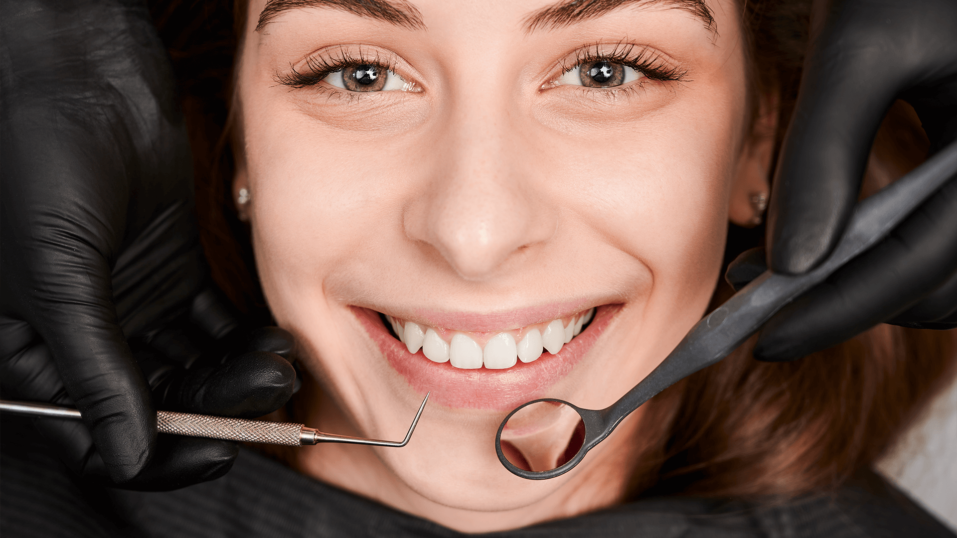 Woman smiling with some visible dentist's tools.