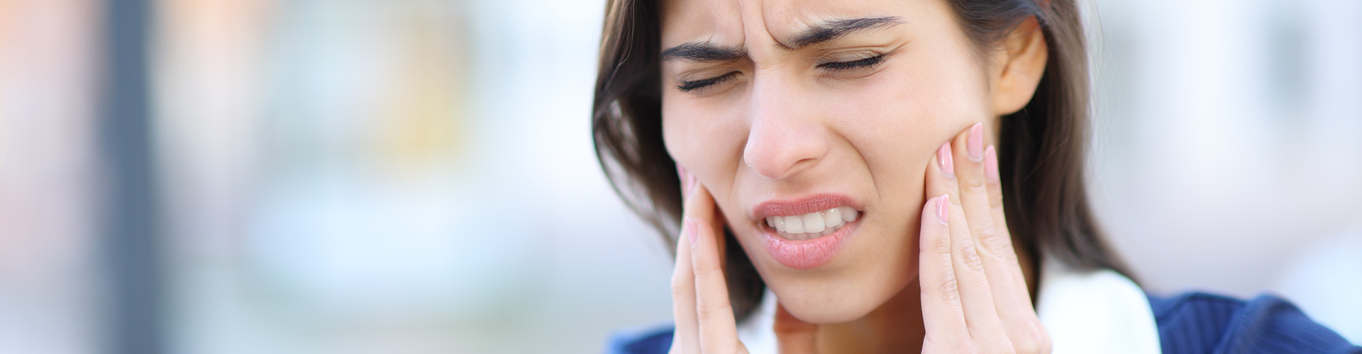 woman grimacing and holding her cheeks.