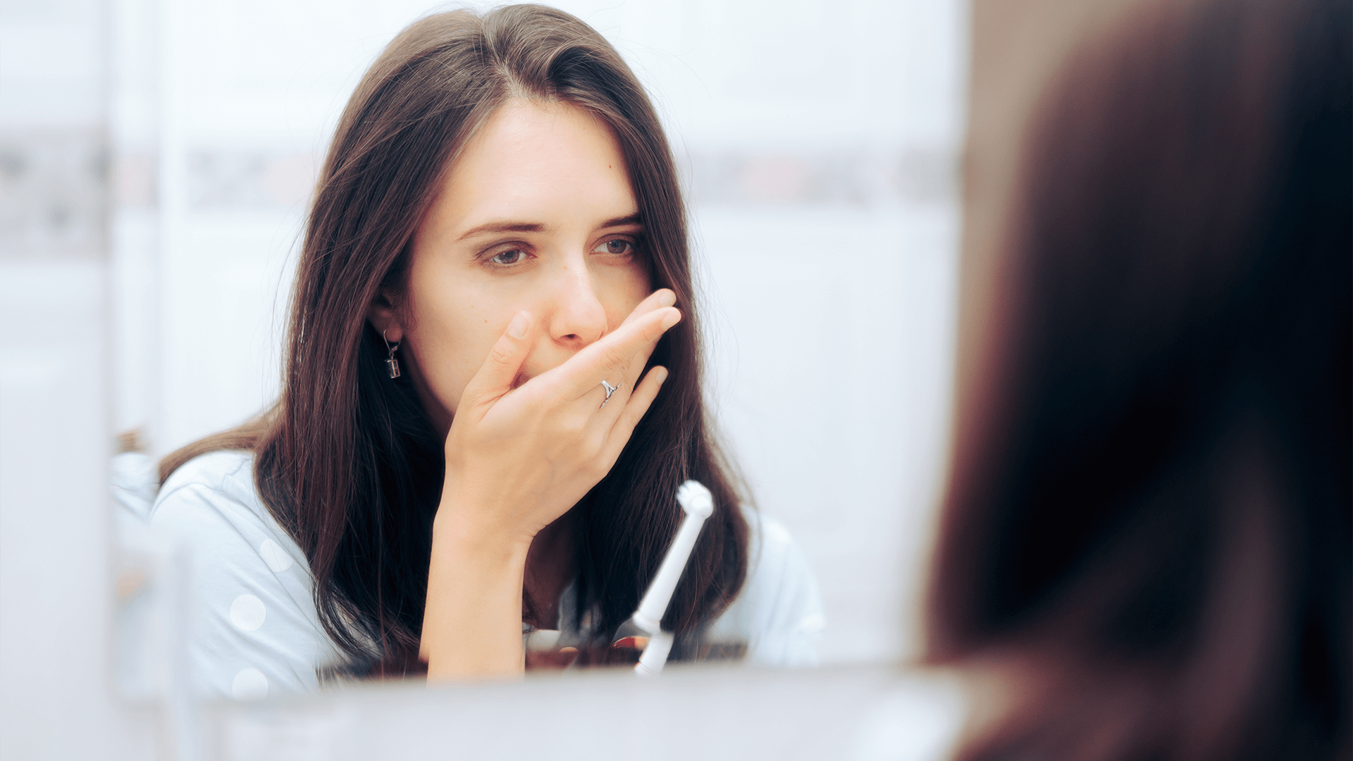 Woman covering her mouth because of pain.