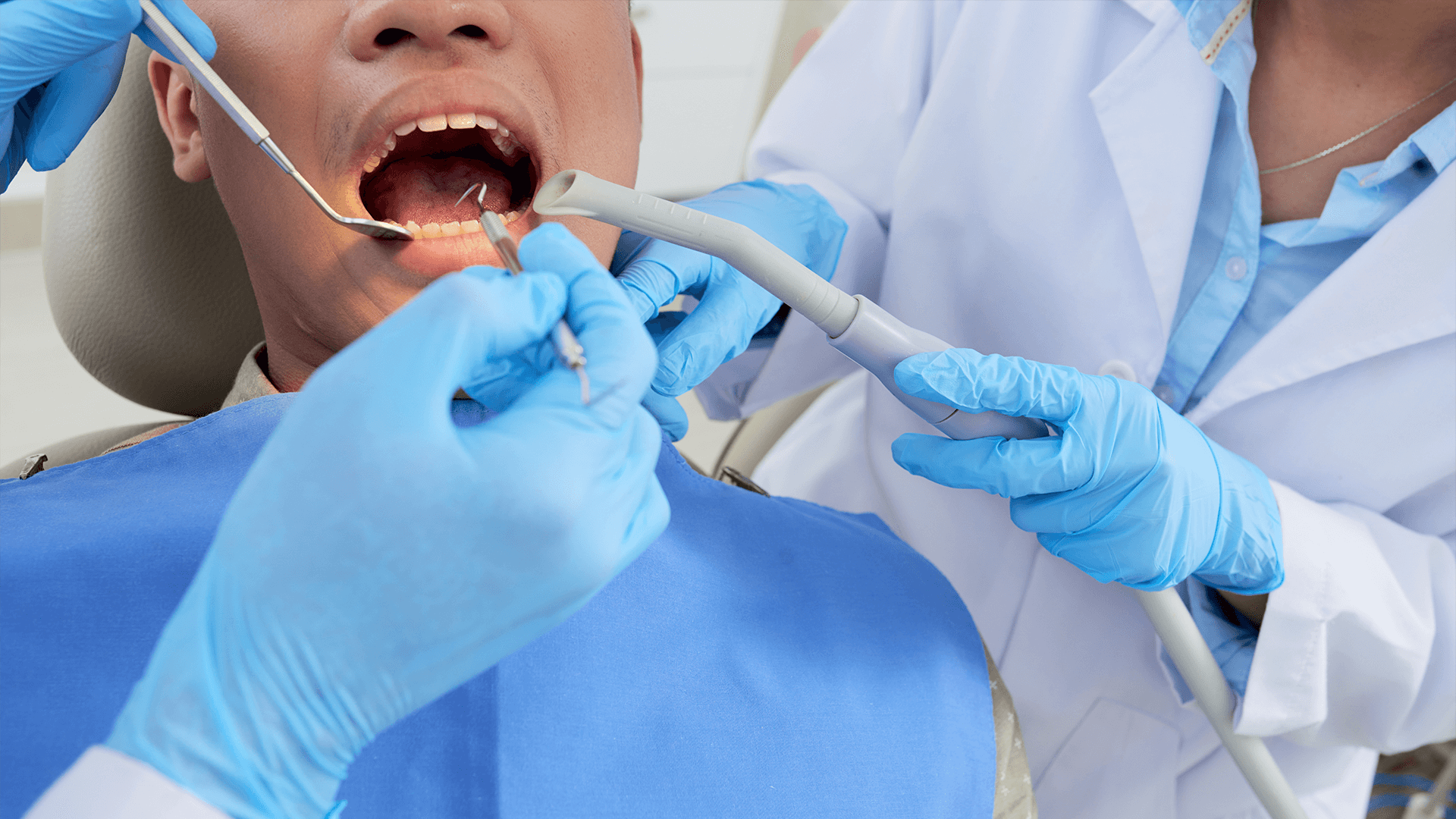 Male patient lying down with mouth open during examination of the teeth.