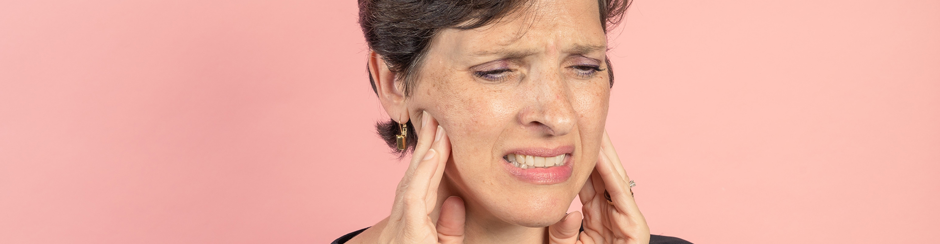 woman holding her jaw in pain.